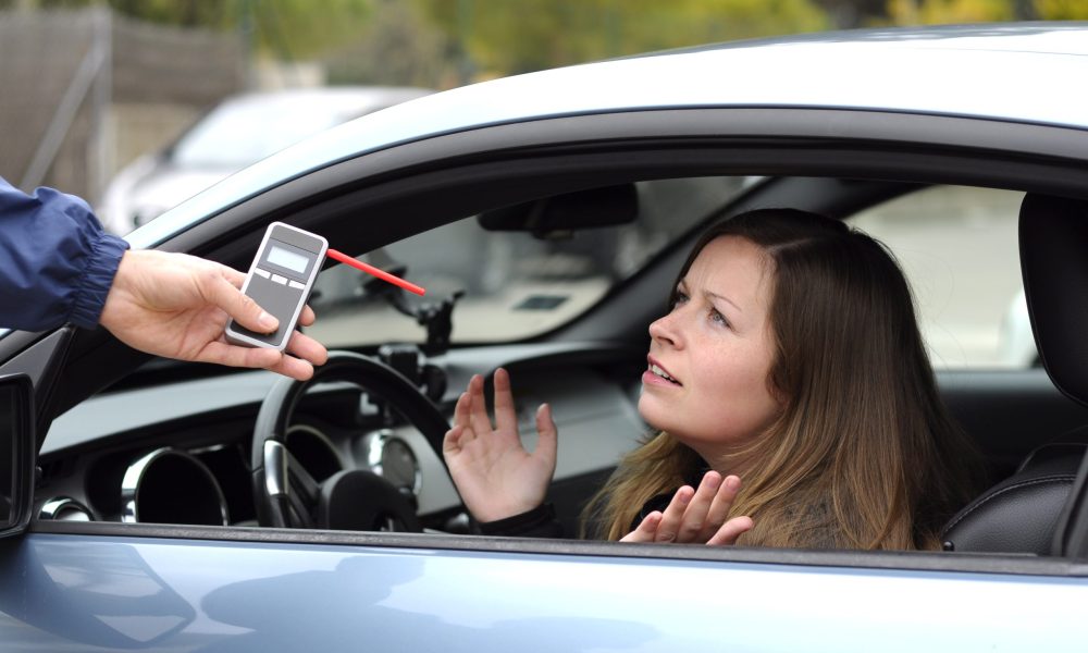 A reluctant woman being administered a breathalyzer test.