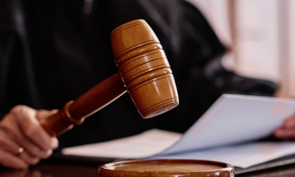 Wooden gavel held by experienced female judge over sounding block.